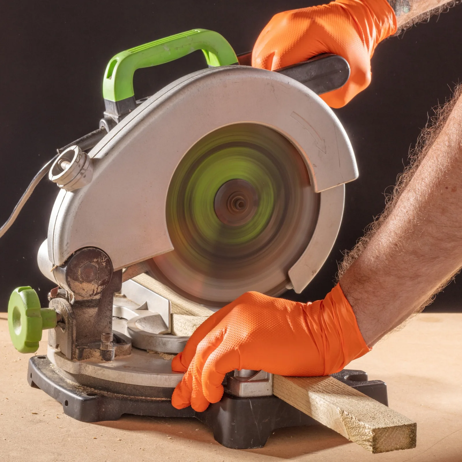 Gator Gripz orange nitrile gloves being used with a mitre saw